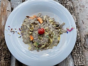 Pizzocheri, typical dish from Grisons, buckwheat pasta, potatoes and cheese served on white ceramic plate.