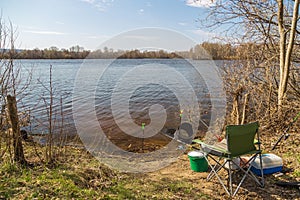 Place angler on the river Bank on a clear Sunny day in the spring. Fishing rods, fishing seat, tank, box of lures. The concept of