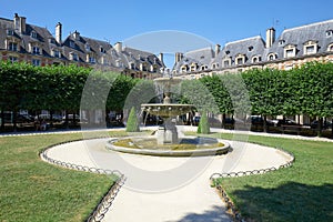 Place des Vosges with fountain in Paris in a sunny morning, clear blue sky