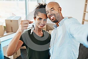 The place is finally ours. Portrait of a young couple taking a selfie while holding the keys to their new home.