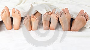 Many children`s feet peeking from under the blanket