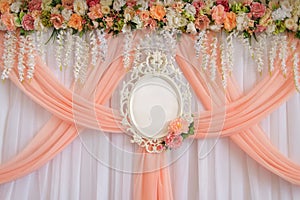 Place for newlyweds decorated with flowers and peach cloth with an empty wedding frame for names of the bride and groom.