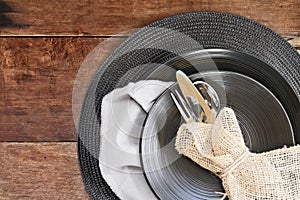 Place Setting of Black Dinnerware over Wooden Background