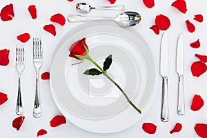 Place setting with red rose and petals