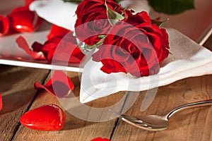 Place setting with red roses in country style