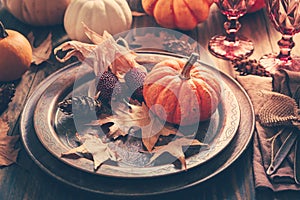 Place setting for Thanksgiving with pumpkins and autumn leaves