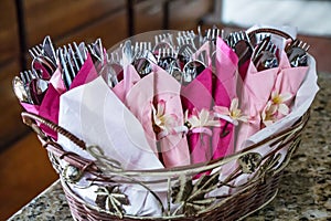 Place settings wrapped with ribbons in a silver basket