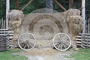Place with stacks of hay cubes and rustic wooden wheels of old cart