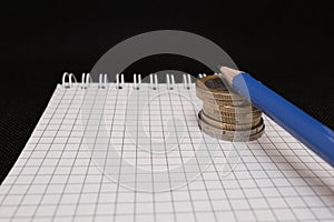 place for text, notebook, graph with pen and euro coins. Close-up of a pen and euro coins on top of a financial graph