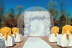 Place for wedding ceremony with white arch and ghairs with yellow cloth outdoors. Empty space for text, copy space.