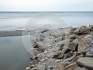 The place where a small river flows into the sea. Winter on the Black Sea. Empty coast. Beach of boulders and small pebbles