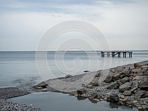 The place where a small river flows into the sea. Winter on the Black Sea. Empty coast. Beach of boulders and small pebbles