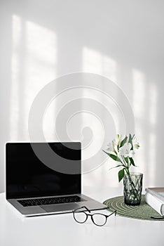 Place of work at home office. Laptop computer, eyeglasses on desk. Business, technology, working from home