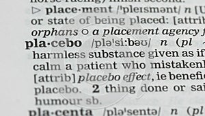 Placebo, pencil pointing word in dictionary, harmless pills, scientific studies