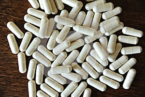 Placer of capsule tablets on a wooden background close up photo