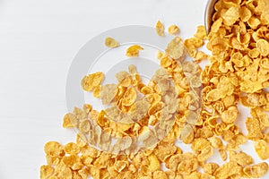 Placer of cornflakes with a metal bowl on a painted white wooden background. Cornflakes scattered on a wooden table. photo