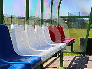 Places for coaches and reserve players on the football field. Plastic colored benches under a canopy of transparent fiberglass. Re