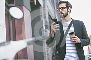 Places to be, people to see. a stylish young man using a cellphone while walking in the city.