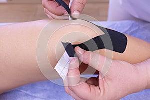 Placing black tape on a knee