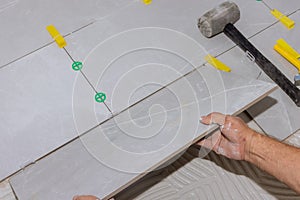 Placing ceramic floor tiles on adhesive surface with home construction working