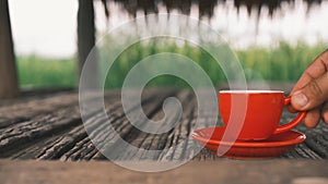 Placing hot ceramic red coffee cup with steam in a saucer on the old wooden floor