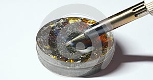 Placing melting solder wire on soldering iron tip. Close-up of hot soldering iron with smoke