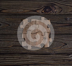 Placing a piece of the puzzle on a textured old wooden table.