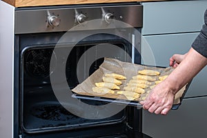 Placing Tray of Unbaked Pastries Into Open Oven in Home Kitchen