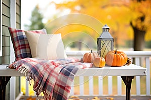 plaid blankets on porch bench with autumn farmhouse backdrop