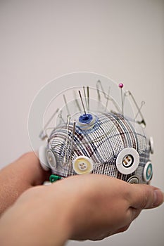 Plaid pin cushion in the hands of seamstresses.Handmade, sewing.