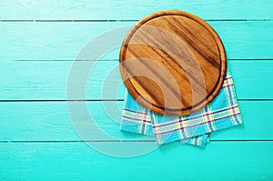 Plaid tablecloth and brown cutting board for pizza on blue wooden background. Top view and copy space. Mock up