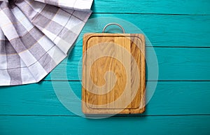 Plaid tablecloth, brown cutting board for pizza on blue wooden table. Wood background. Top view and mock up.Copy space