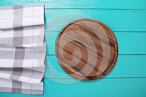 Plaid tablecloth, brown cutting board for pizza on blue wooden table. Wood background. Top view and mock up.Copy space