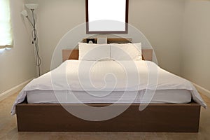 Plain bedroom interior, white pillows and mattress use white linen on wooden bed