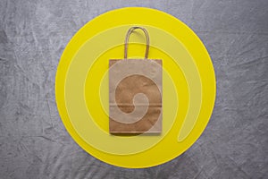 Plain brown paper bag on a yellow circle and gray background