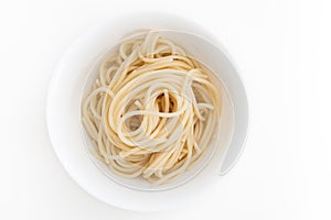 Plain cooked spaghetti pasta in white bowl, on white background.