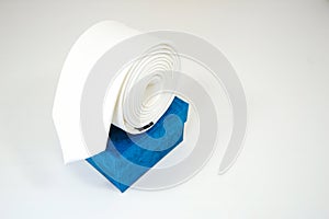 Plain fabric white tie rolled on gift box with white background close-up view