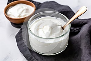 plain greek yogurt in a bowl with a spoon beside