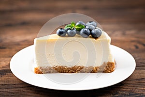 Plain New York Cheesecake Slice Topped With Blueberries And Mint Leaf