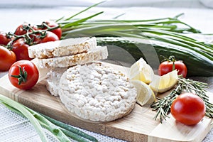 Plain rice cakes, galette rice with lemon, rosemary and vegetables on wooden board