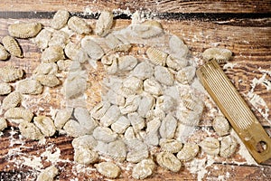 Plain view of finished raw fresh gnocchi on wooden background with manual gnocchi maker