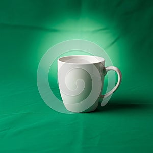 A plain white ceramic mug is centered against a green backdrop