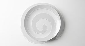 A plain, white ceramic plate sits on a smooth, light gray surface. The plate is circular