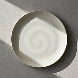 A plain white ceramic plate on a textured light gray surface