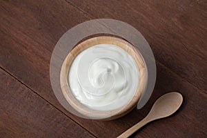 Plain yoghurt in wooden bowl on wood table