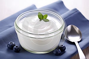 plain yogurt in a ceramic bowl with a silver spoon