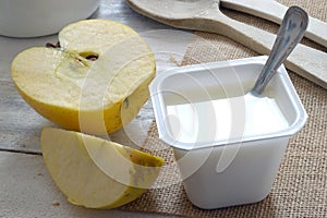 Plain yogurt on a sack cloth with an apple