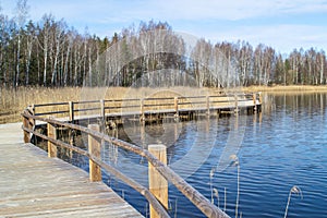 Plains quarry in Olaine, Latvia. Wooden path along the lake. Lake shore, reeds and trail.