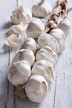 Plait of white garlic on white wooden background