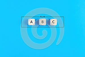 Plan a, b and c on wooden cubes on blue background. Choosing a business strategy plan